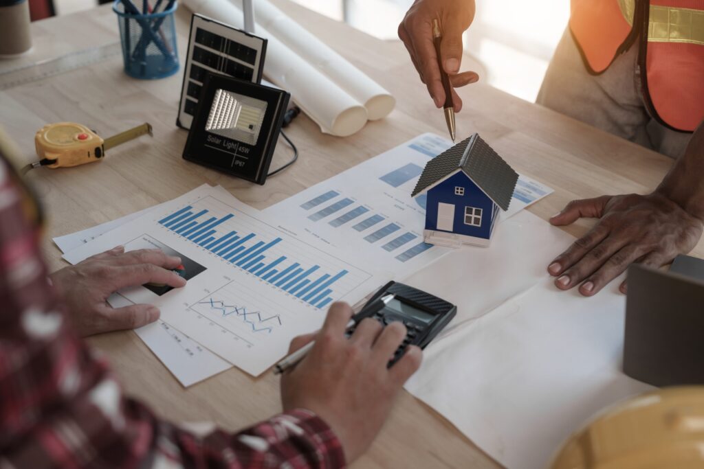 Zwei Personen planen eine Solaranlage mit Modellhaus und Wirtschaftlichkeitsanalyse auf dem Tisch